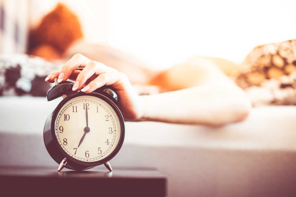 woman shutting off alarm clock