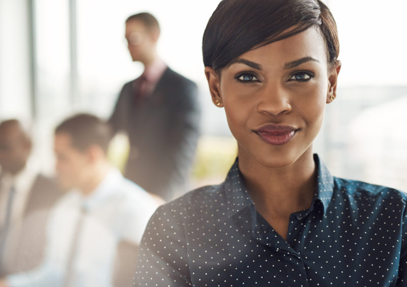 confident business woman in office with group