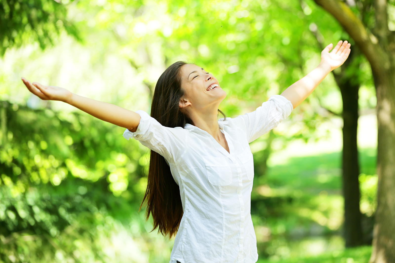 young woman meditating with open arms standing in fresh spring g